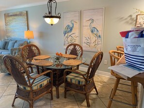 A dining area with a round glass table surrounded by wicker chairs with striped cushions.