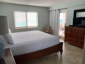 Une chambre à coucher avec un grand lit, une commode, une chaise et un téléviseur.
