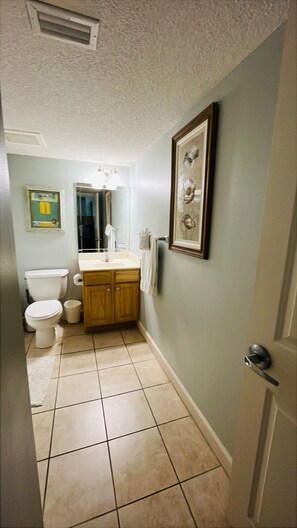 Une salle de bain équipée de toilettes, d’un lavabo, d’un meuble-lavabo et d’œuvres d’art encadrées accrochées au mur.
