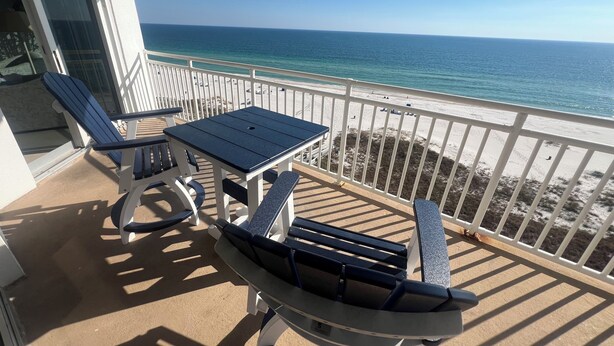 A balcony with a table and chairs, overlooking a beach and the ocean. - SeaSpray 1006 Gulf Front Penthouse,Pool,Tennis (Pensacola)