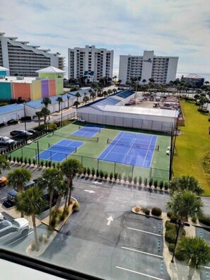 Un edificio de varios pisos con un complejo de canchas de tenis.