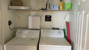 Un área de lavandería con dos lavadoras de carga frontal, un secador y un refrigerador pequeño.
