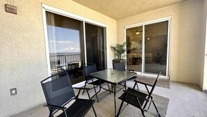 A balcony with a glass door, a table, and four chairs.