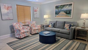 A living room with a gray sofa, two patterned armchairs, a round coffee table, and a striped rug.