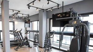 Uma academia moderna com diversos equipamentos de exercícios, janelas amplas e um espaço limpo e arejado.