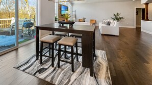 Cocina moderna con una isla central, taburetes de bar y un amplio ventanal con vistas a una terraza.