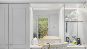A modern bathroom with a vanity, a mirror, a glass shelf with toiletries, and a view of greenery outside. - Cottage Suite 2, Kentisbury Grange -  Free WiFI & Parking (Barnstaple)