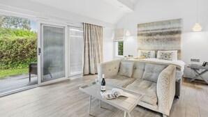 A modern bedroom with a large bed, a sofa, and a dining table. There is a sliding glass door leading to a balcony. - Cottage Suite 2, Kentisbury Grange -  Free WiFI & Parking (Barnstaple)