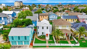 A residential area with houses, a white picket fence, and a clear view of the ocean. - Heated Pool | Pet Friendly | Fire Pit | Near Beach (Galveston)