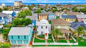 A residential area with houses, a white picket fence, and a clear view of the ocean.