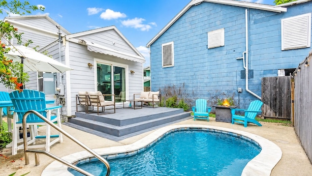 Un pati amb piscina, mobiliari exterior i una casa blava.