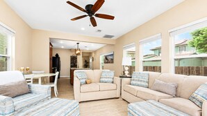 A spacious living room with a ceiling fan, a dining area, and a kitchen in the background. - Heated Pool | Pet Friendly | Fire Pit | Near Beach (Galveston)