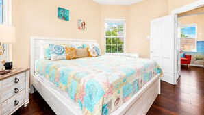 A bedroom with a bed, a nightstand, a dresser, and a window. - Heated Pool | Pet Friendly | Fire Pit | Near Beach (Galveston)