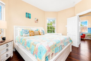 A bedroom with a bed, a nightstand, a dresser, and a window.