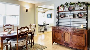 A dining area with a wooden table and chairs, a chandelier, and a decorative wall with plates and a clock. - In-Town Home, Hot Tub, Wifi & Minutes to Skiing (Red Lodge)