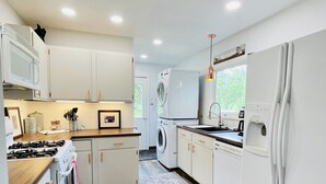 A modern kitchen with white cabinets, a red rug, and a washing machine. - In-Town Home, Hot Tub, Wifi & Minutes to Skiing (Red Lodge)