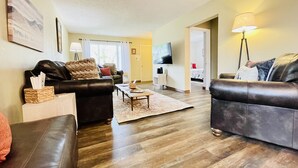 A living room with two leather sofas, a coffee table, a flat-screen TV, and a lamp. - In-Town Home, Hot Tub, Wifi & Minutes to Skiing (Red Lodge)