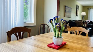 A dining area with a wooden table, chairs, and a vase with flowers. - In-Town Home, Hot Tub, Wifi & Minutes to Skiing (Red Lodge)