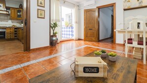 Un espacio habitable amplio con una mesa de madera, un letrero que dice 'HOME' y vista hacia la cocina.