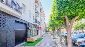 Una calle con pavimento a cuadros, coches estacionados y árboles a lo largo de la acera.