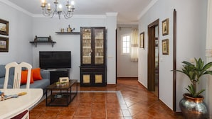 Una sala de estar con sofá, televisión y una mesa de comedor.