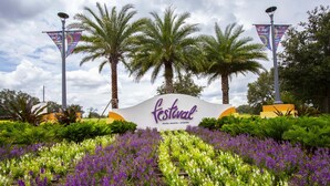 A sign for a festival with a garden of purple and white flowers in front. - Charming 3Bd Close To Disney At Enclaves At Festival 745 (Davenport)