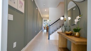 A hallway with a wooden console table, a mirror, and a staircase with a railing. - Charming 4Bd W/ Private Pool @ Storey Lake Resort 2653 (Kissimmee)
