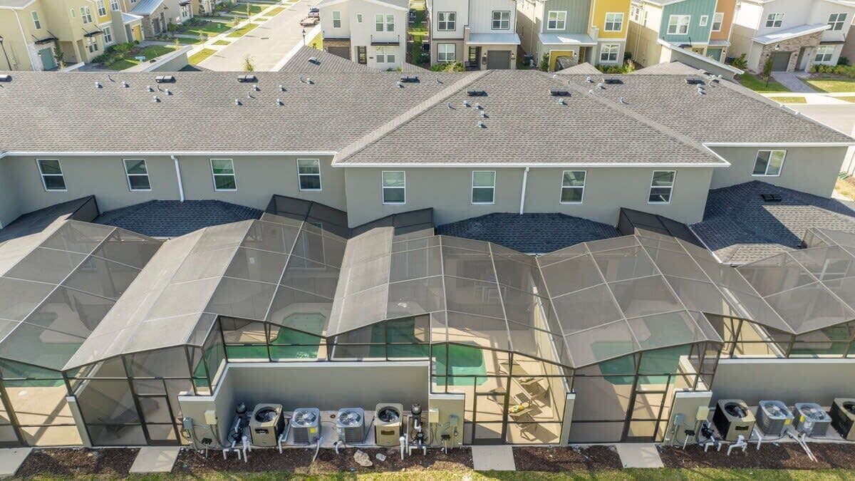 Un edificio residencial con varias unidades, cada una con jardín en la azotea y paneles solares.