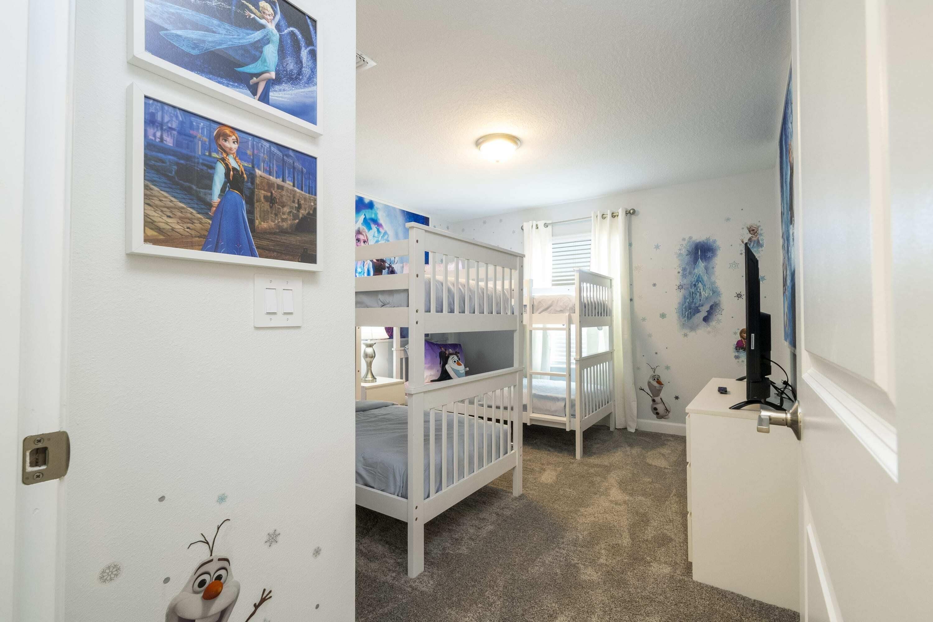 A child's bedroom with bunk beds, wall decorations, and a small desk.