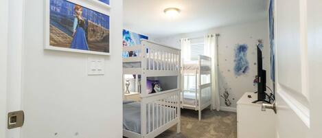 A child's bedroom with bunk beds, wall decorations, and a small desk.