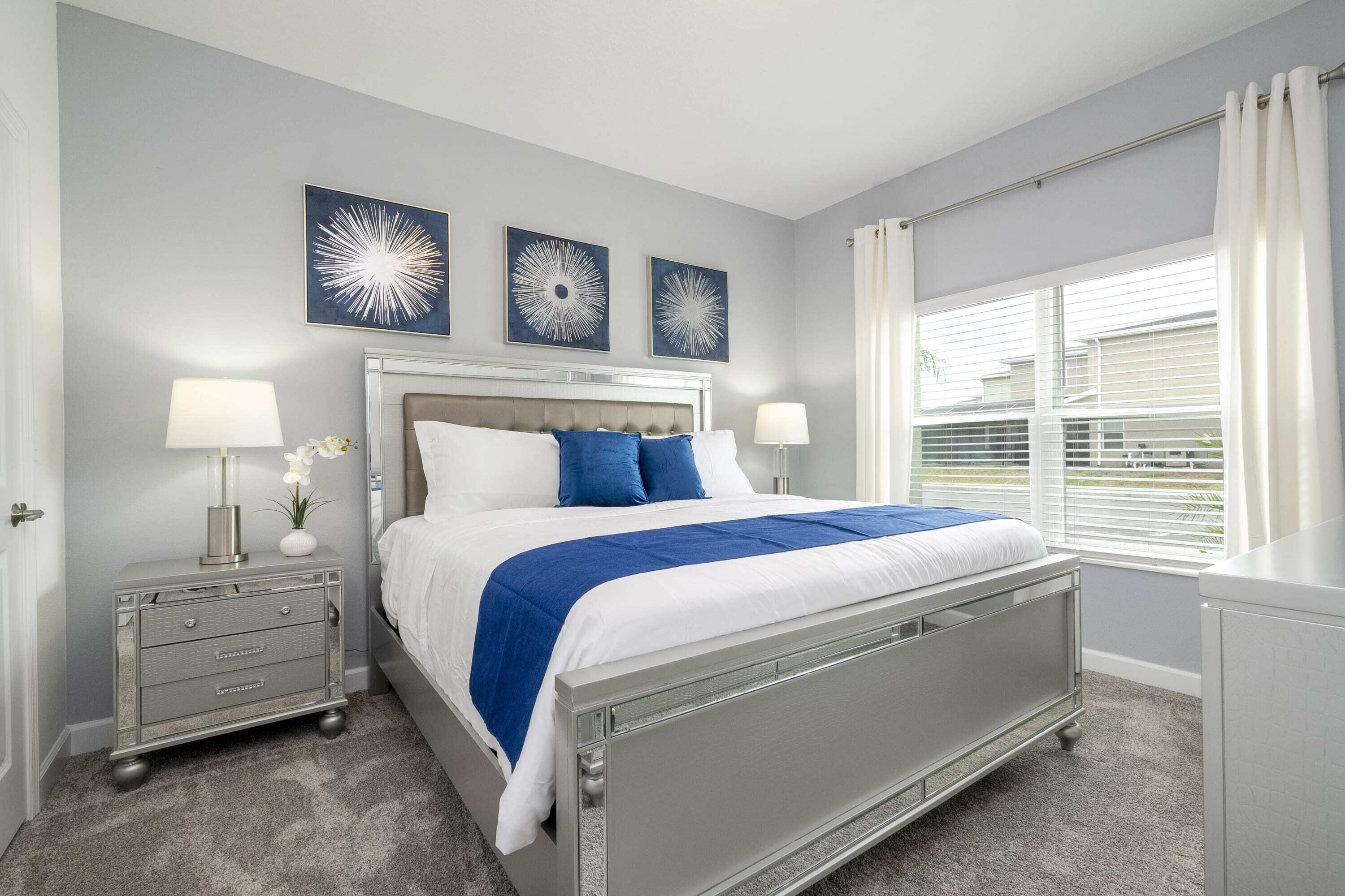 A bedroom with a bed, bedside tables, and artwork on the wall.