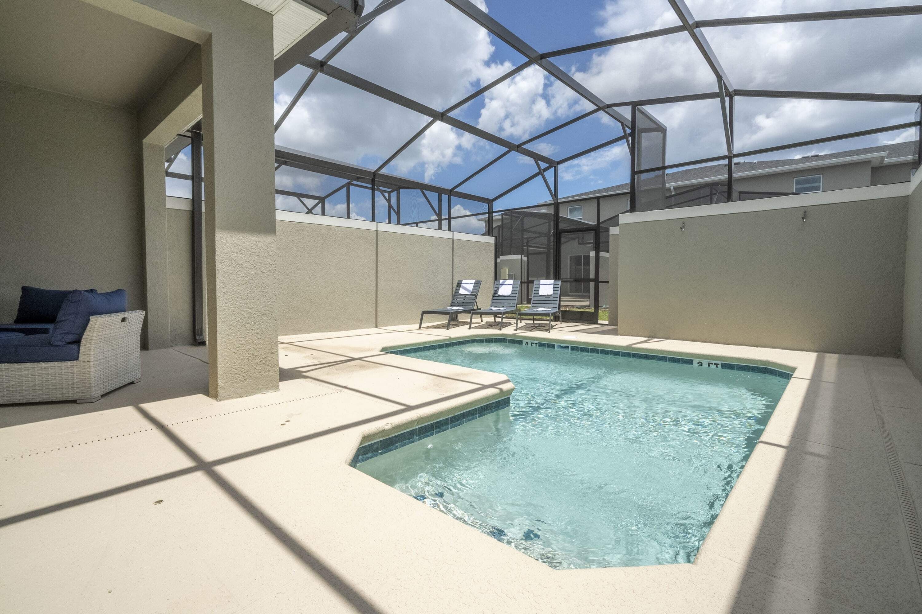 An indoor swimming pool with a glass ceiling, lounge chairs, and a sofa.