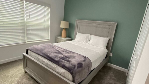 A bedroom with a bed, a nightstand, a lamp, and a window with blinds. - Free Waterpark 5Bd Close To Disney W/ Pool @ Storey Lake Resort 2497 (Kissimmee)