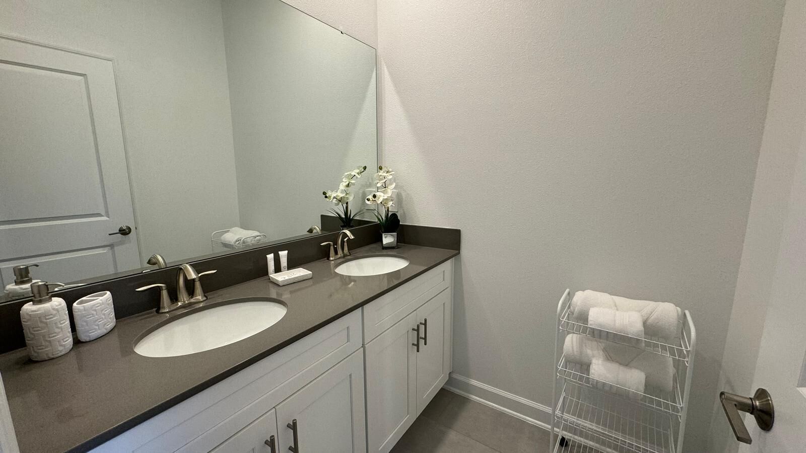A bathroom with two sinks, a large mirror, a towel rack, and toiletries.