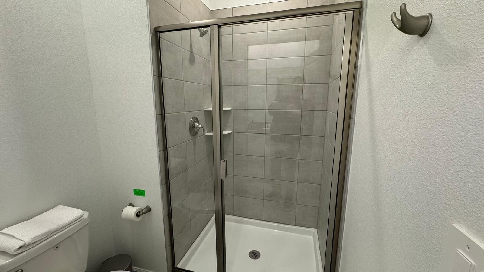 A shower with a glass door, a toilet with a towel, and a wall-mounted towel rack.