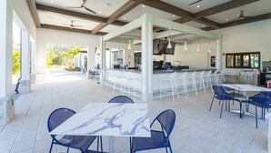 A spacious outdoor patio with a bar area, seating arrangements, and ceiling fans.