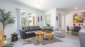 A modern living room with a grey sofa, two round wooden tables, a leopard print rug, and a dining area with a table and chairs.