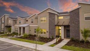 A row of modern townhouses with stone facades, small front yards, and a parking lot.