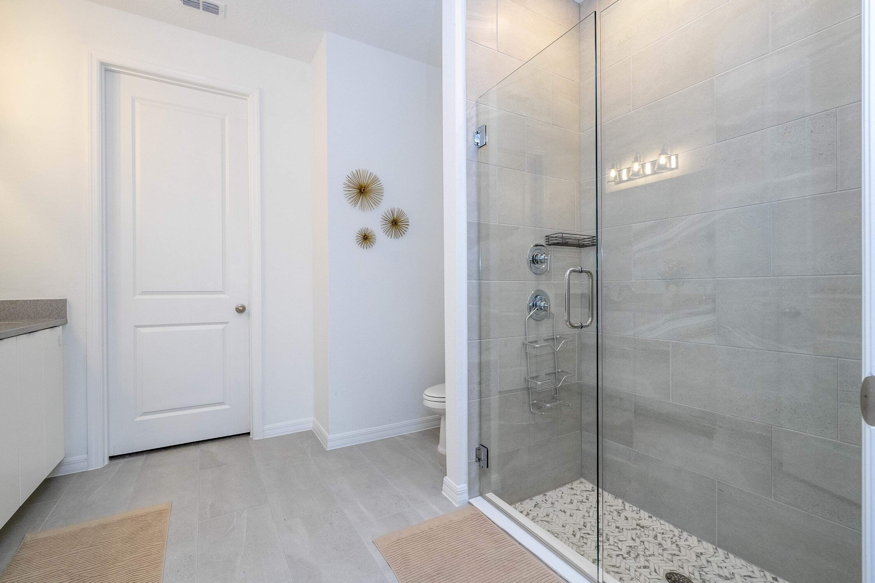 A modern bathroom with a glass-enclosed shower, a white toilet, and decorative wall art.