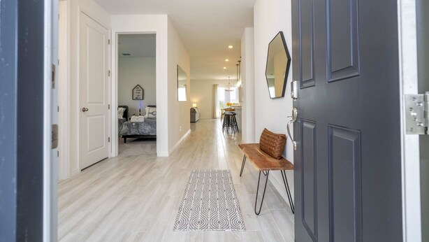 A hallway with a patterned rug, a bench, and a door with a mirror. - Gorgeous 4Bd W/ Gameroom Close To Disney @ Glen West Haven 2198 (Davenport)