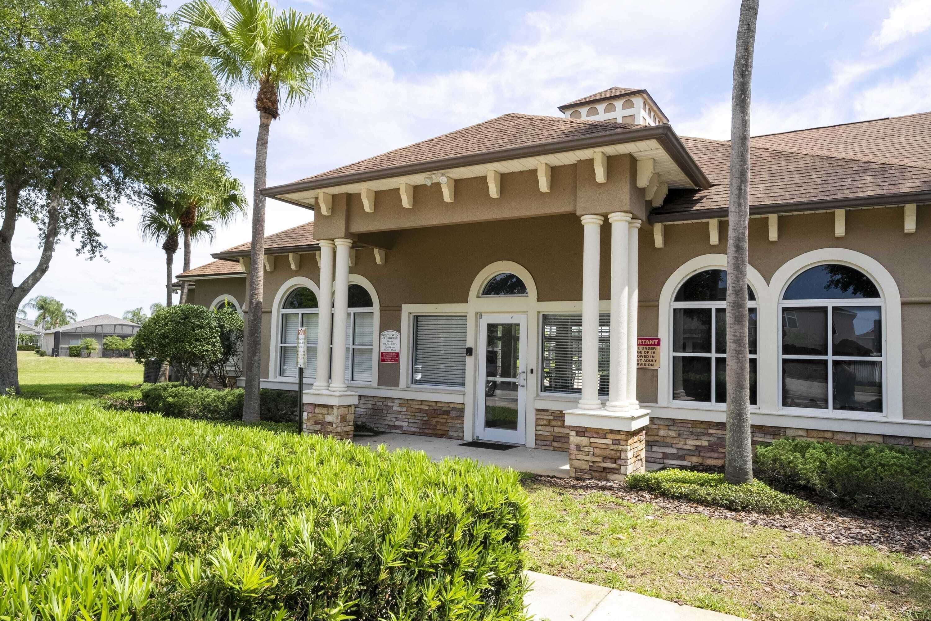 A two-story building with a brown facade, white trim, and a covered front porch with columns.