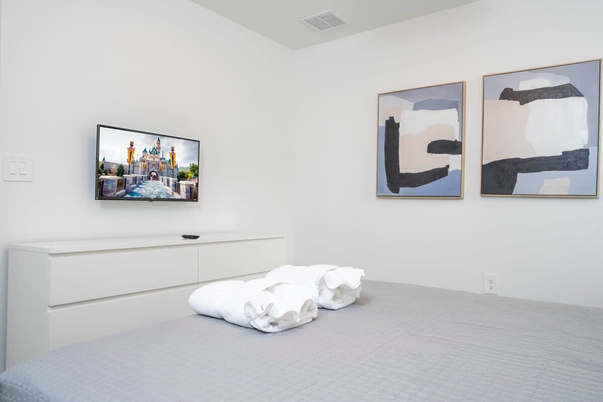 Habitación de hotel con una cama, un televisor de pantalla plana en la pared y obras de arte abstracto.