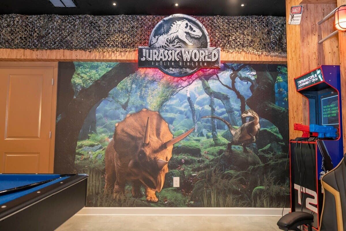 A room with a mural of a dinosaur and a sign reading "Jurassic World Fallen Kingdom".