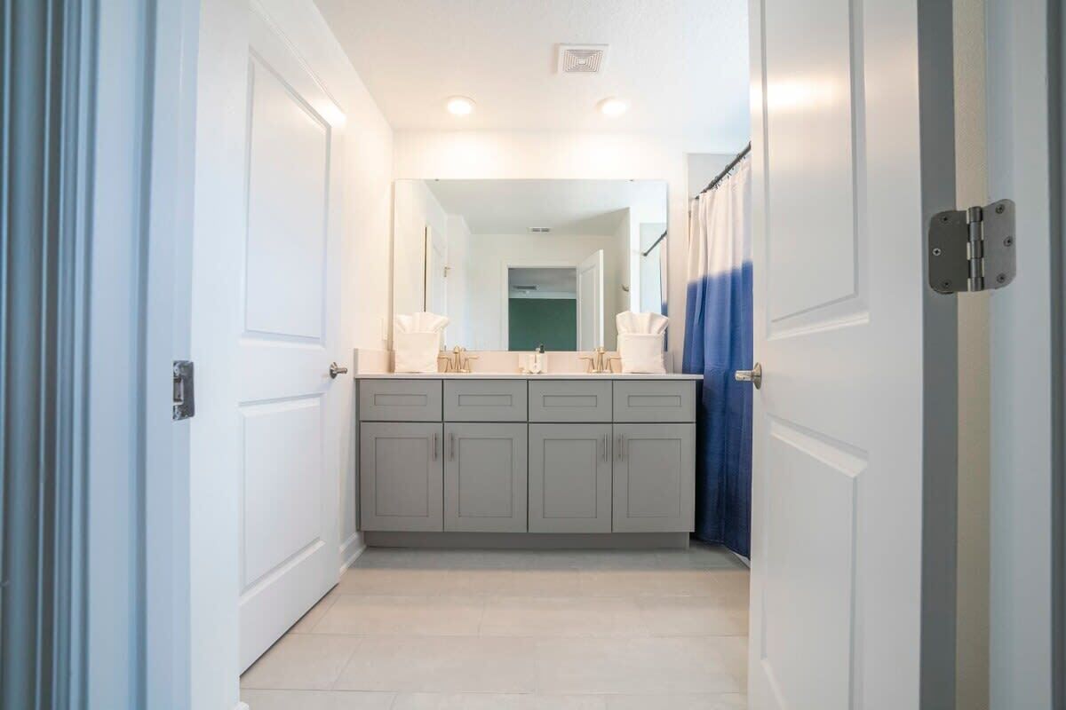 A narrow hallway with a bathroom vanity, a mirror, and a door with a curtain.