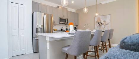 A modern kitchen with a central island, stainless steel appliances, and pendant lighting.