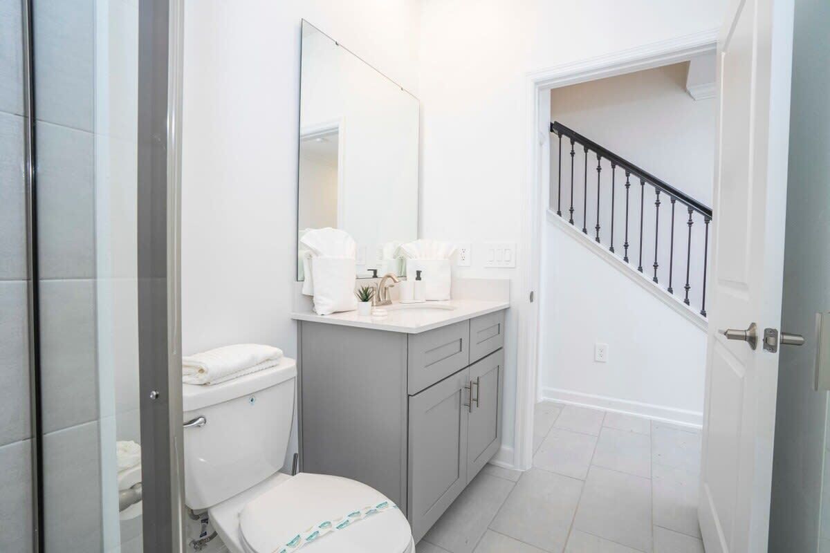 A bathroom with a toilet, sink, and mirror.