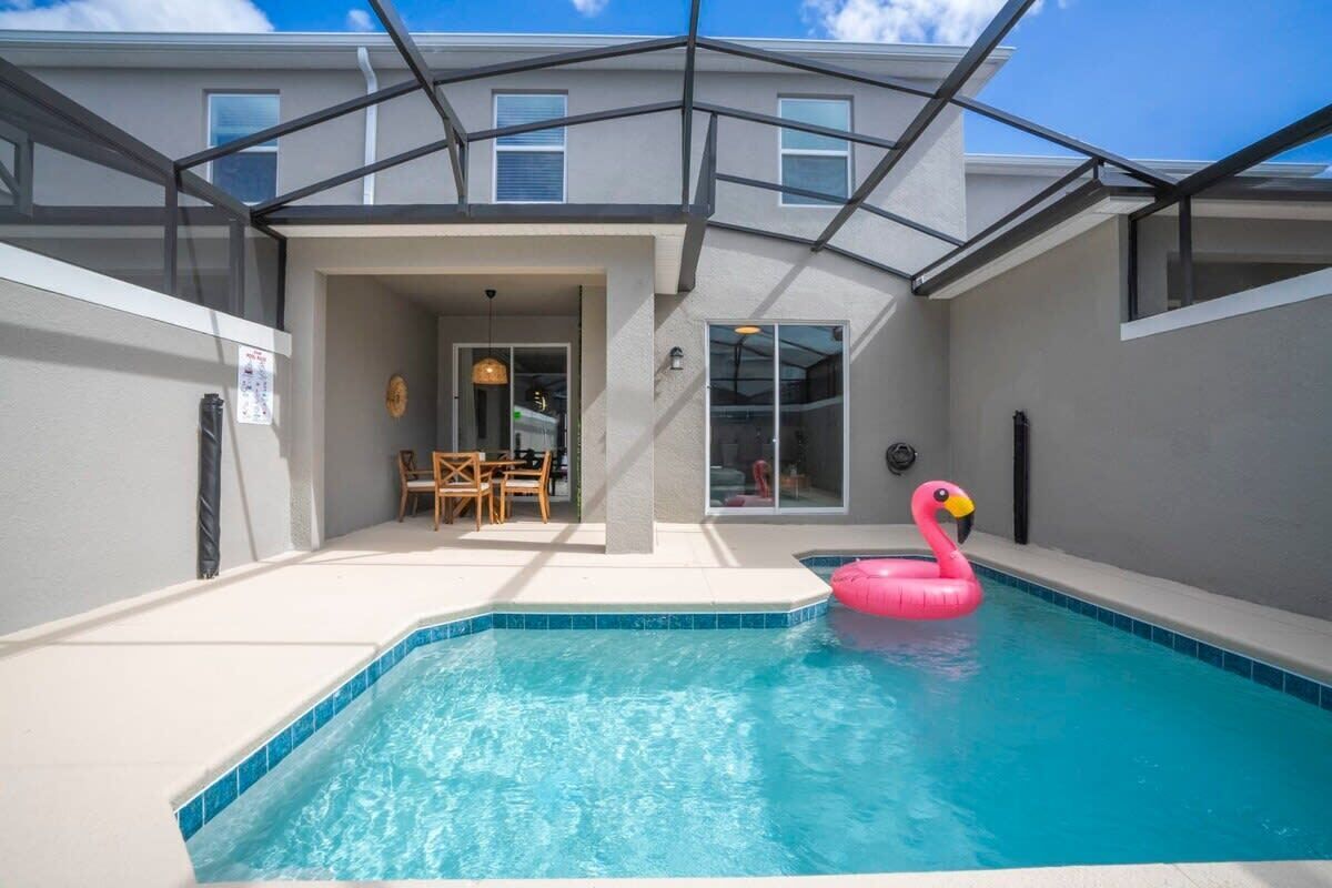 Ein Schwimmbecken mit einem rosa Flamingo-Schwimmpfad, einer überdachten Terrasse und Blick zum Himmel.