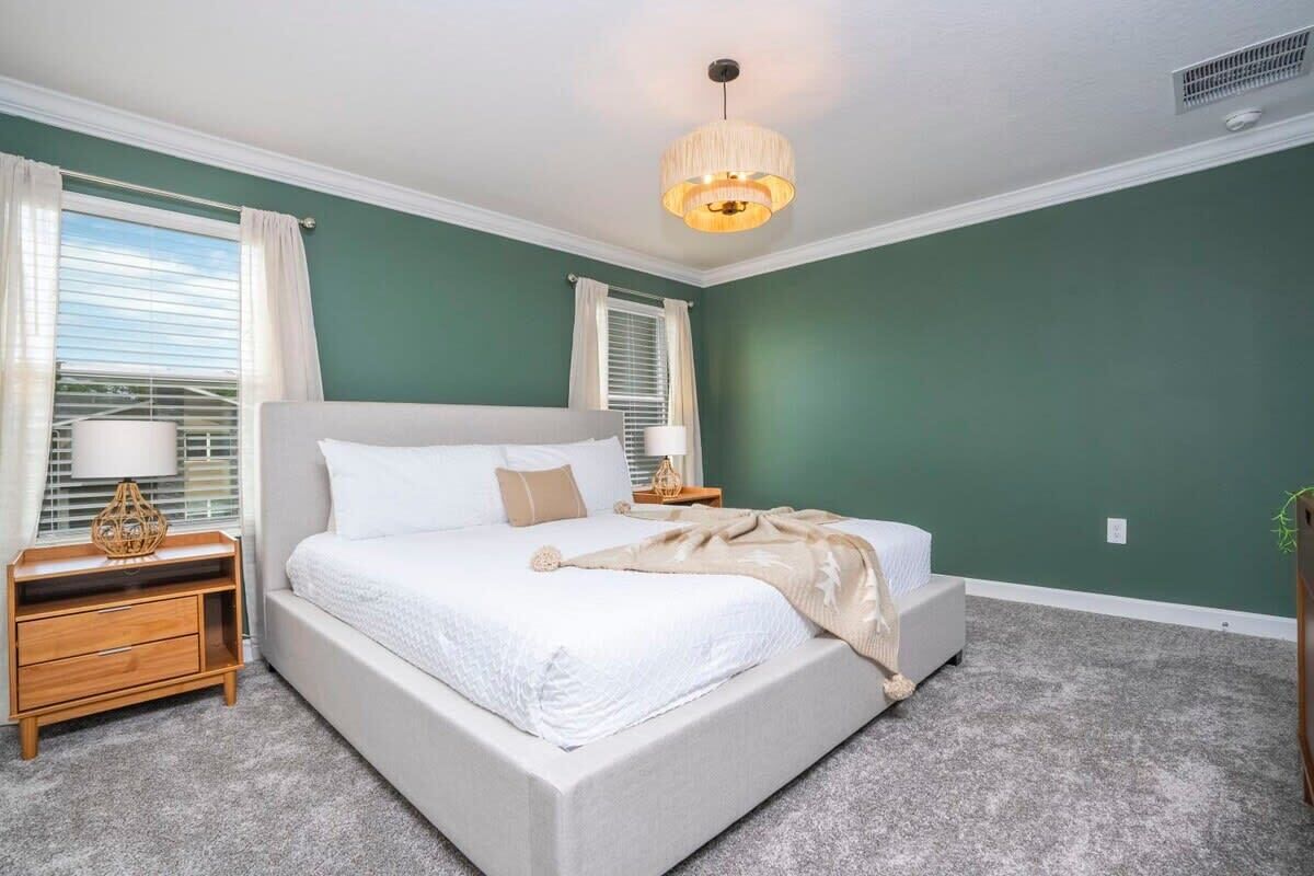 A bedroom with a bed, nightstands, a lamp, and a ceiling light.