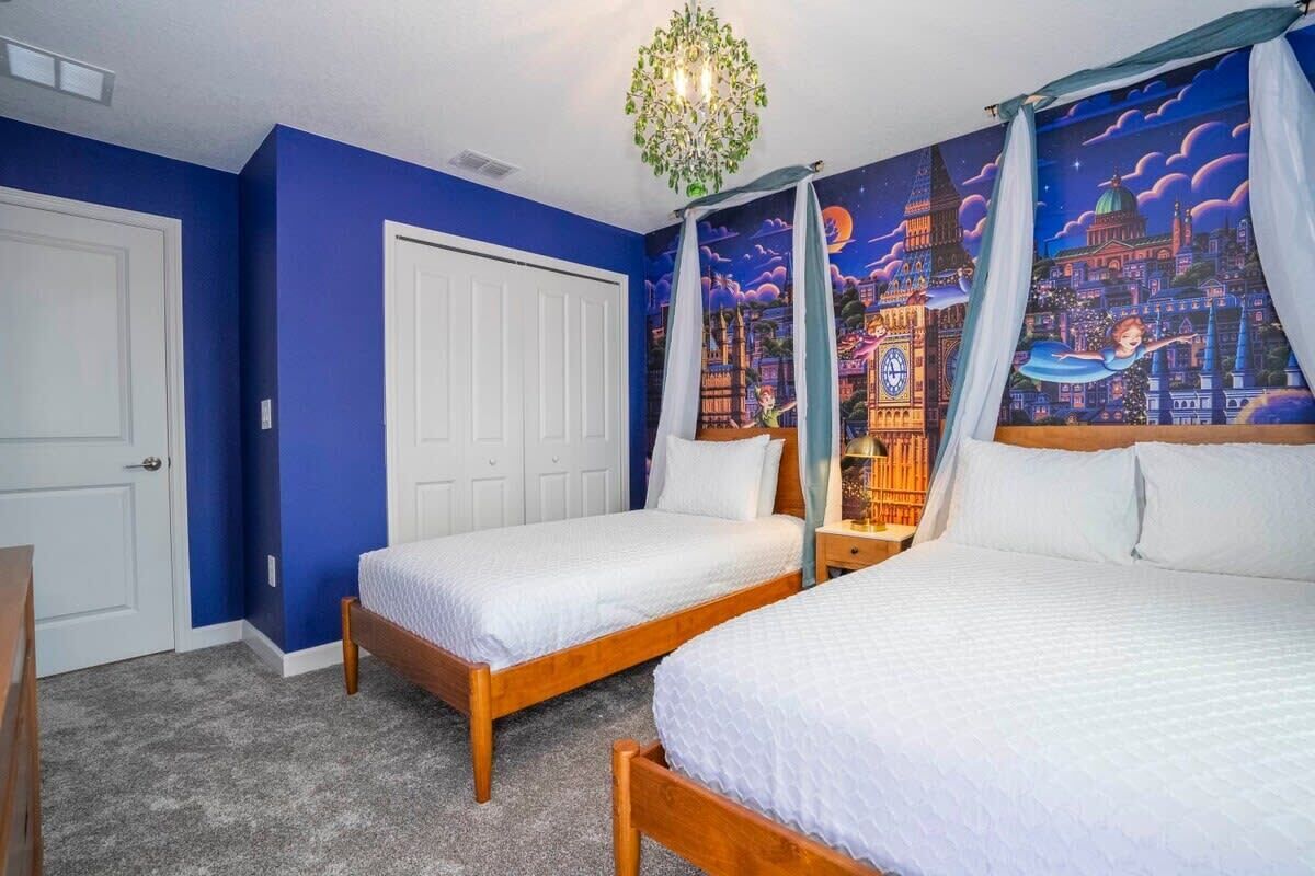 Une chambre avec deux lits, dont un lit à baldaquin, une fresque représentant un paysage urbain et un lustre.