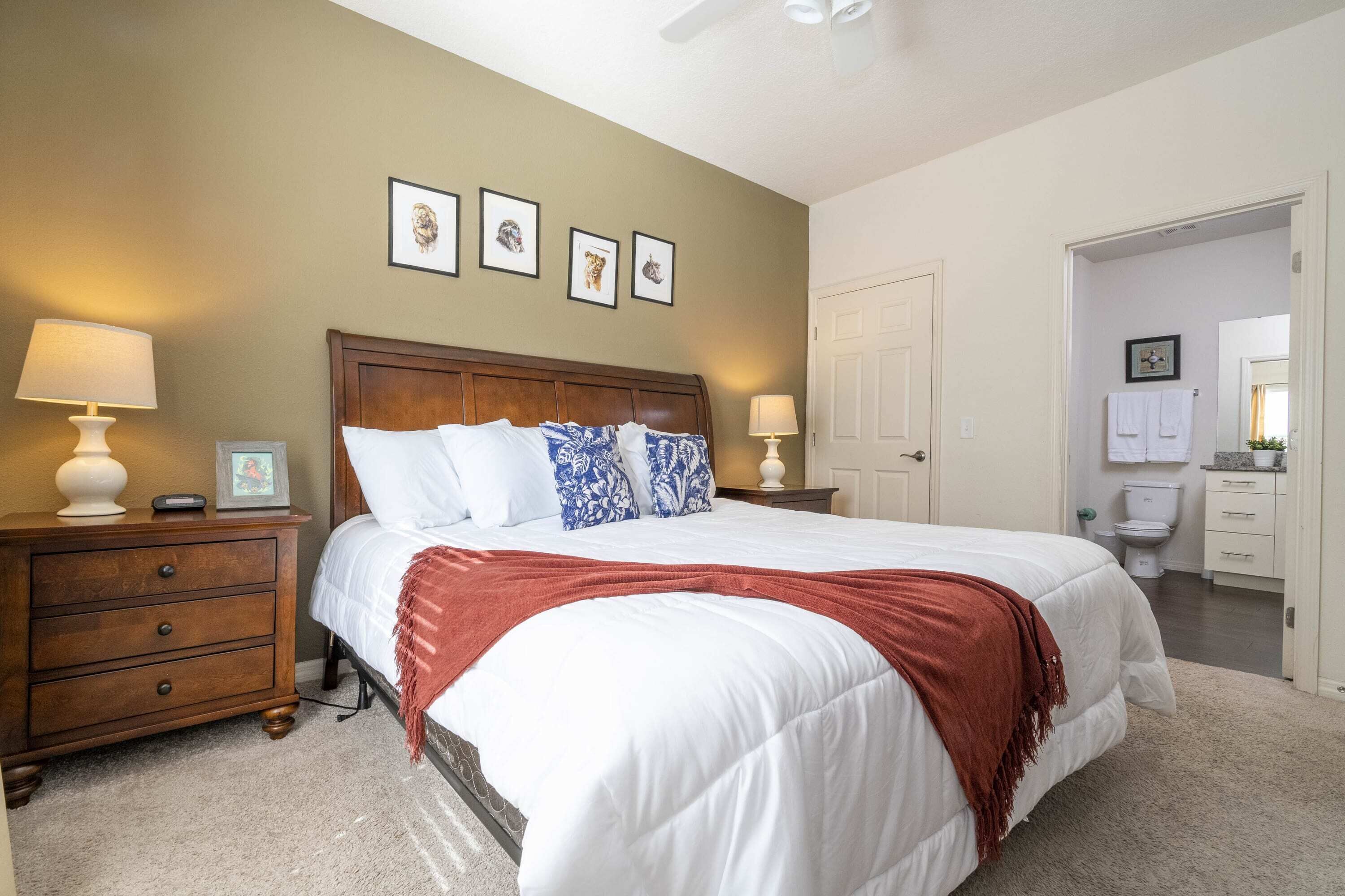 Une chambre à coucher avec un grand lit, des tables de chevet en bois, une commode et une porte donnant sur une salle de bain.